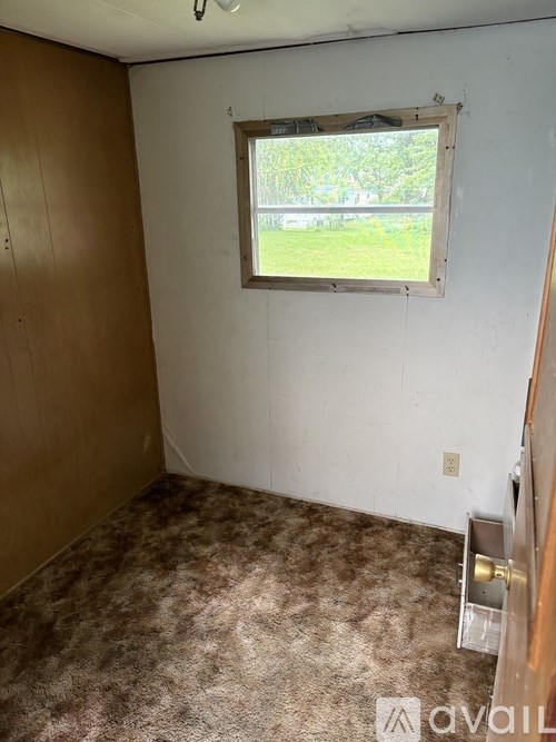 A room with a window and a carpeted floor.
