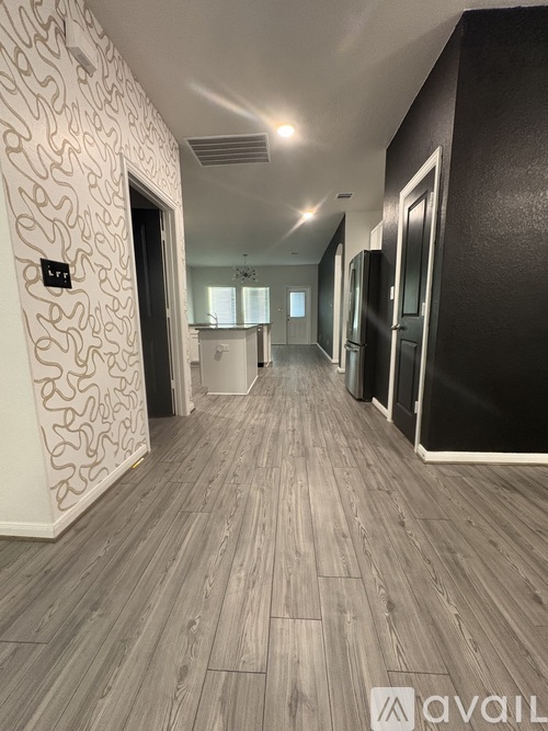A hallway with wooden floors and a patterned wallpapered wall.
