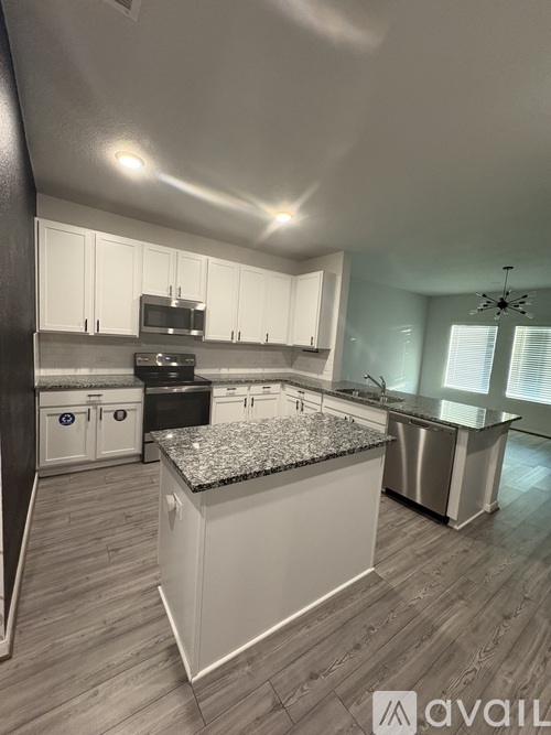 A kitchen with a granite countertop and stainless steel appliances.