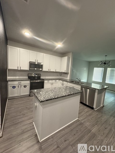 A kitchen with a granite countertop and stainless steel appliances.