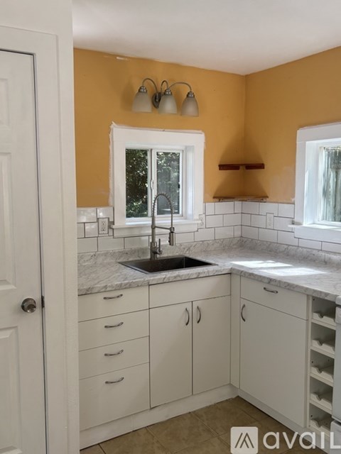 A kitchen with white cabinets and a marble countertop.
