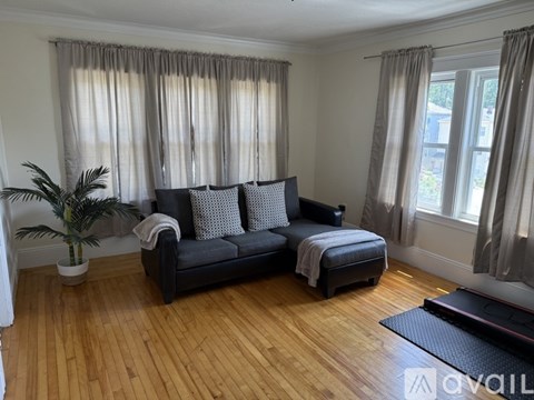 A living room with a black couch and wooden floors.