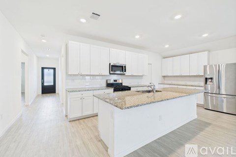 A modern kitchen with white cabinets and stainless steel appliances.