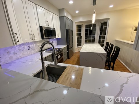 A kitchen with a marble countertop and a dining table with chairs.