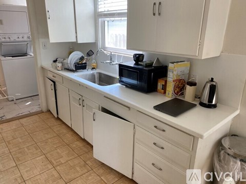 A kitchen with white cabinets and a black microwave.