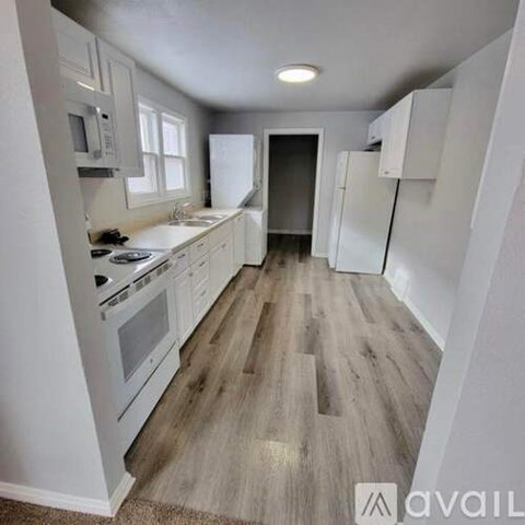 A kitchen with white appliances and wooden floors.