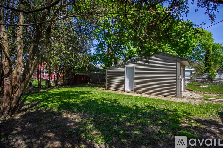 A small house with a metal roof is surrounded by trees and grass.