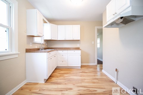 A kitchen with white cabinets and wooden floors.