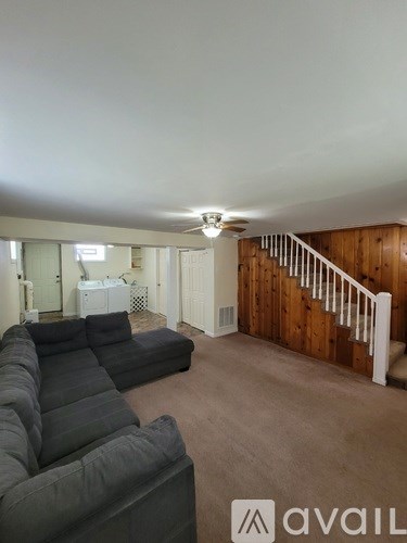 A living room with a grey couch and a white staircase.
