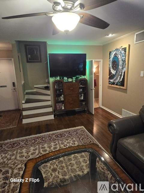 A living room with a television and a rug.