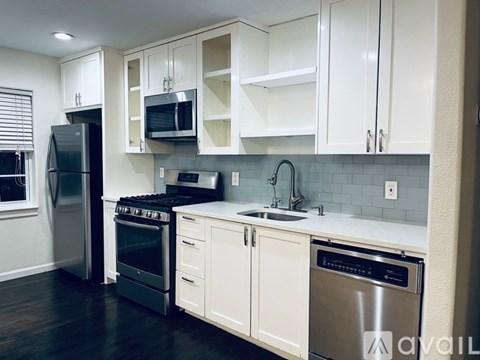 A kitchen with white cabinets and a black fridge.