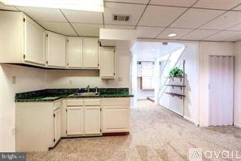A kitchen with white cabinets and a green countertop is available for rent.