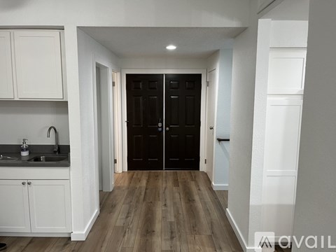 A kitchen with white cabinets and a black door.