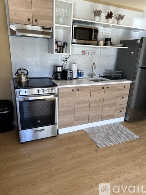 A kitchen with wooden floors and a refrigerator on the right.