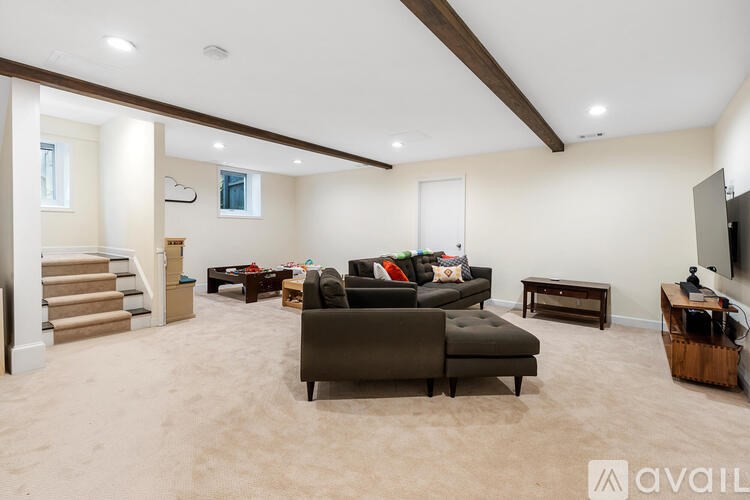A living room with a brown couch and a television on the wall.