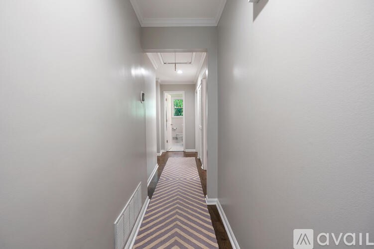 A long, narrow hallway with a striped carpet and white walls.