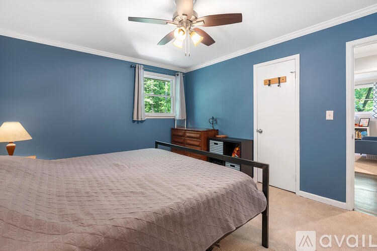 A bedroom with a bed, a ceiling fan, and a window with a view of trees.