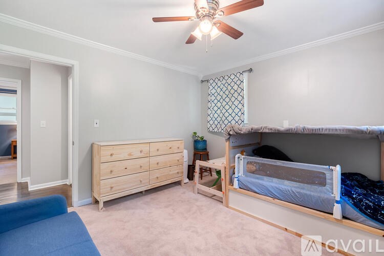 A bedroom with a bunk bed, dresser, and a ceiling fan.