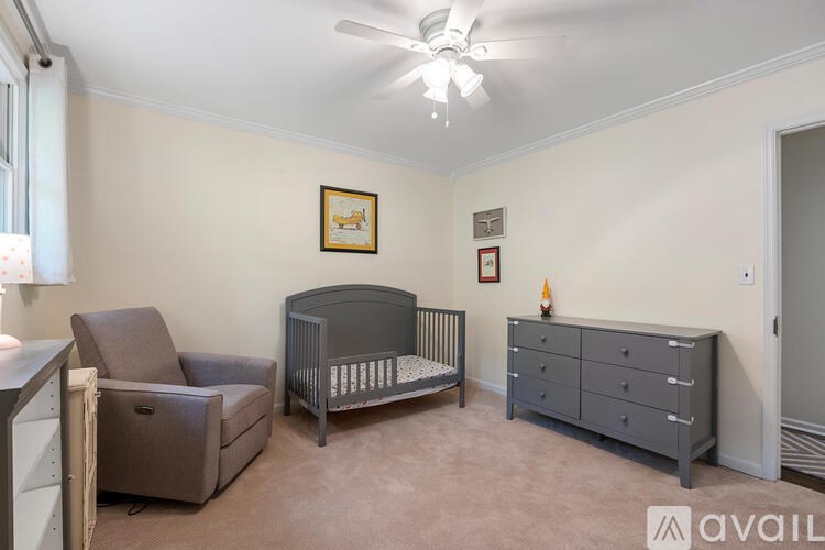 A baby room with a crib, dresser, and chair.