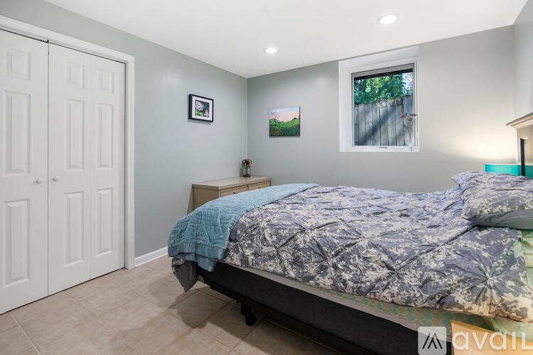 A bedroom with a bed, a window, and a painting on the wall.