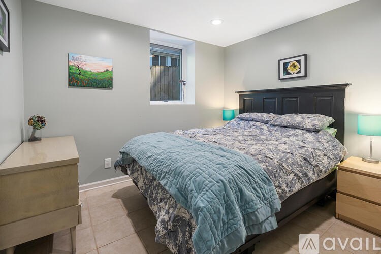 A bedroom with a bed, nightstand, and a painting on the wall.