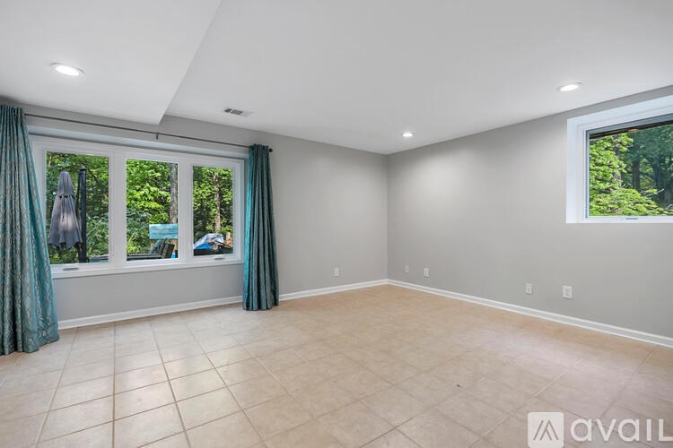 A spacious room with a large window and a view of trees outside.