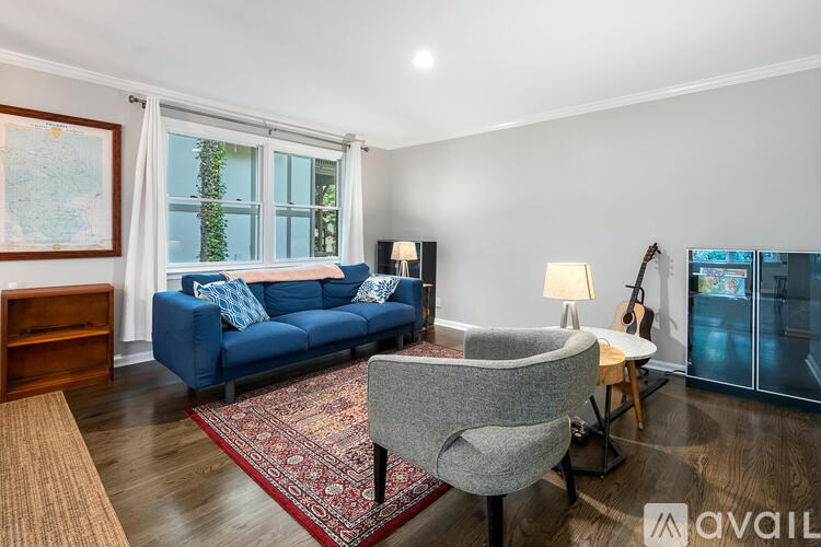 A living room with a blue couch, a grey armchair, and a rug.