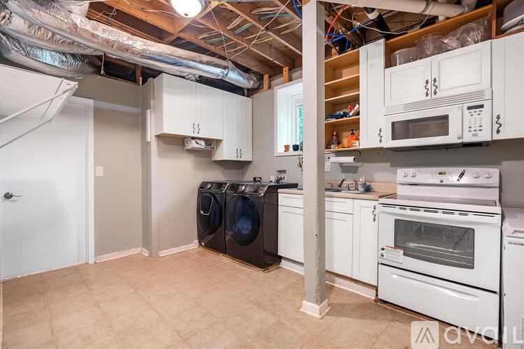 A kitchen with white appliances and cabinets, and a washer and dryer in the laundry area.