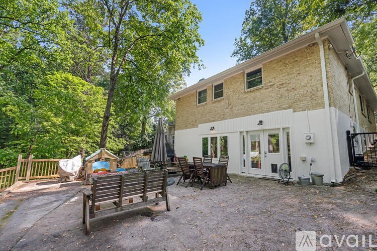 A house with a patio and a deck is surrounded by trees.