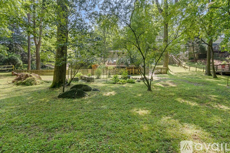 A lush green yard with trees and a wooden fence.