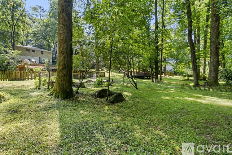 A lush green park with trees and a fence.