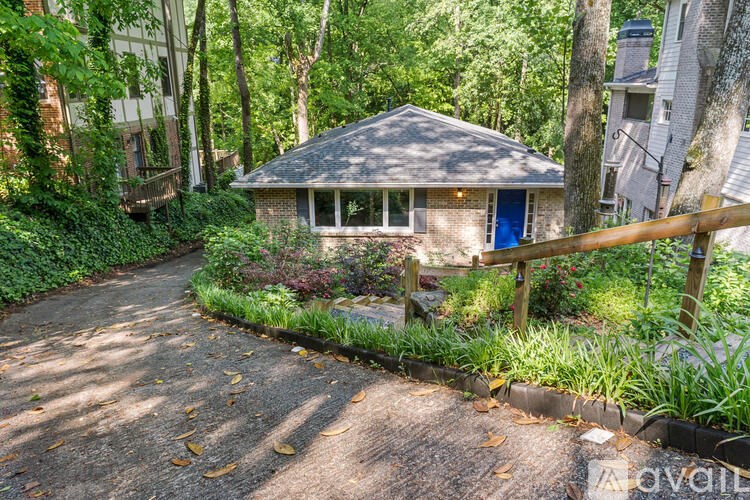 A small house with a blue door is surrounded by greenery.