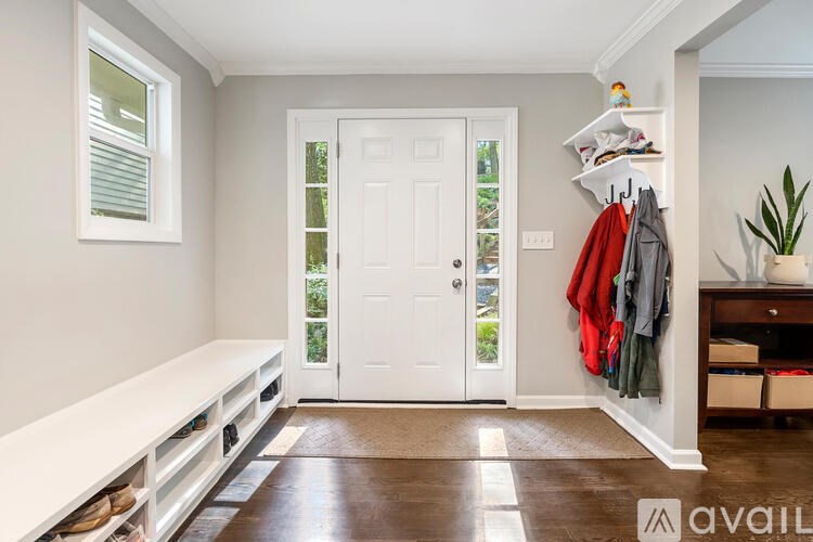 A hallway with a bench, coat rack, and a door.