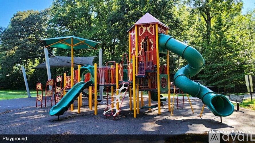A playground with a green and yellow slide and a red and yellow tower.