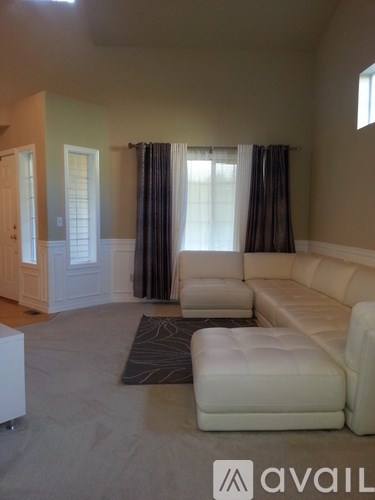 A living room with a white couch and a rug.