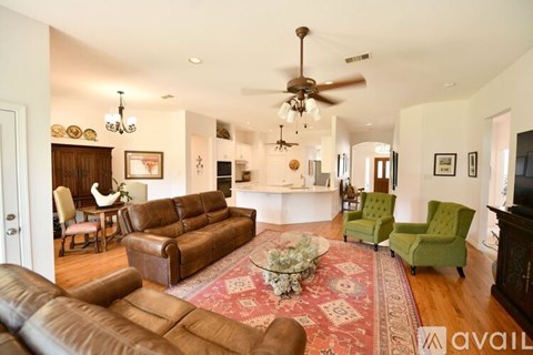 A living room with a brown leather couch and a red rug.