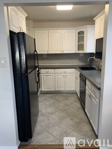 A kitchen with a black fridge and white cabinets.