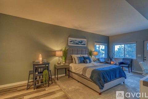 A bedroom with a bed, nightstand, and chair.
