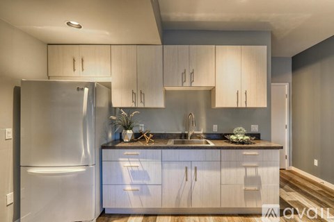 A kitchen with a stainless steel refrigerator and wooden cabinets.