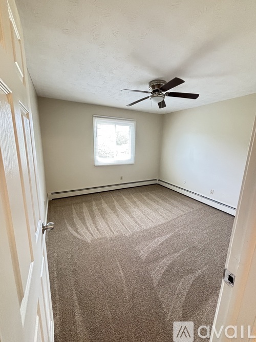 A room with a carpeted floor and a ceiling fan.