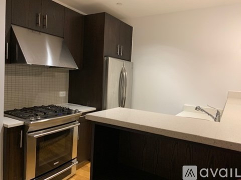 A kitchen with dark brown cabinets and a stainless steel range hood.