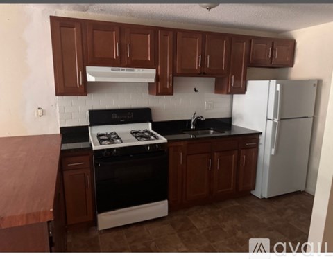 A kitchen with brown cabinets and a white stove top oven.