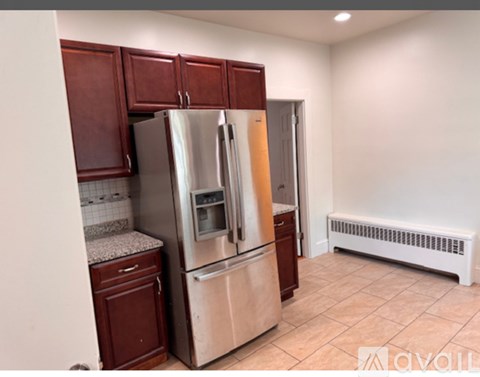 A kitchen with a stainless steel refrigerator and wooden cabinets.
