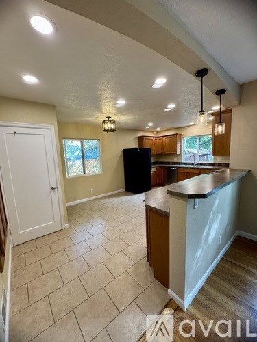 A kitchen with a black refrigerator and wooden cabinets.