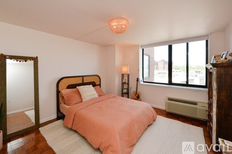 A bedroom with a bed, a mirror, a lamp, and a guitar.