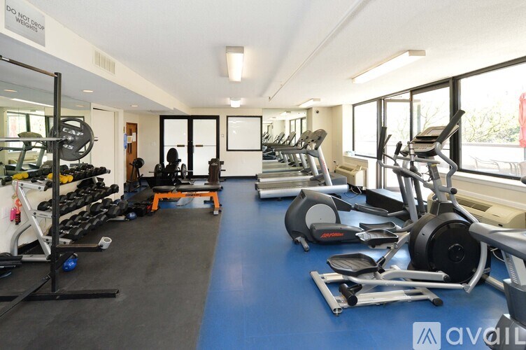 A gym with a variety of exercise equipment including treadmills, stationary bikes, and weight machines.