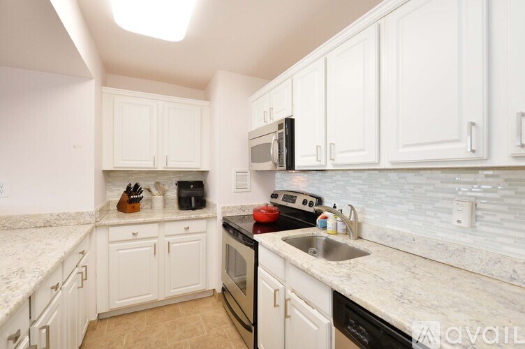 A kitchen with white cabinets and a marble countertop.