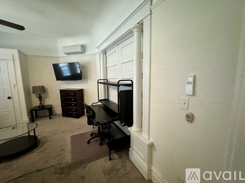 A living room with a black couch and a television on the wall.