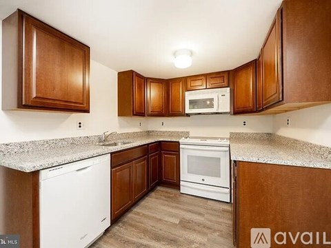 A kitchen with brown cabinets and a white dishwasher.