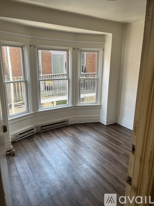 A room with a large window and wooden flooring.